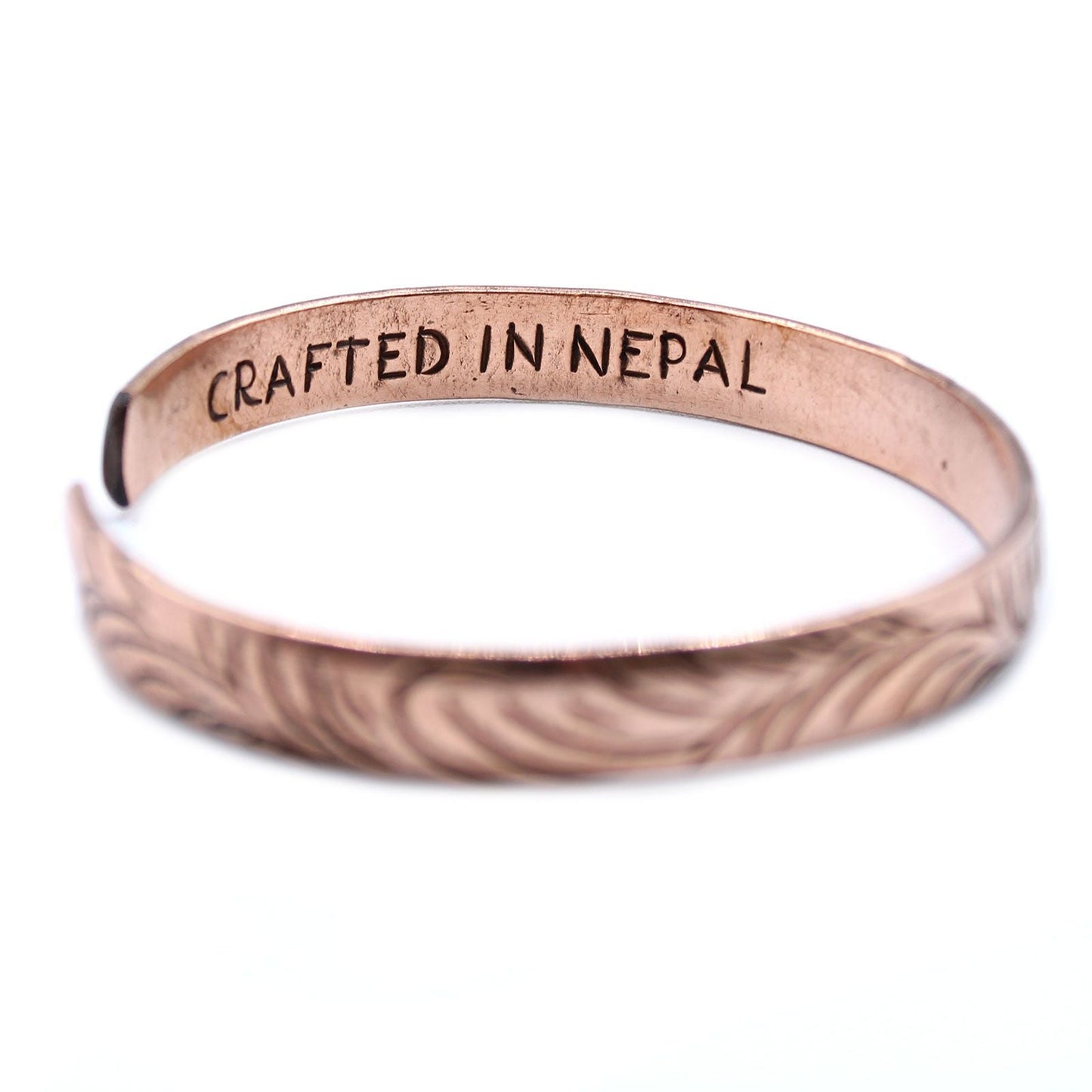 Alt Tag: Solid Copper Tibetan Bracelet – Slim Tribal Swirls, slim copper cuff bracelet with tribal swirl engraving and “CRAFTED IN NEPAL” stamp