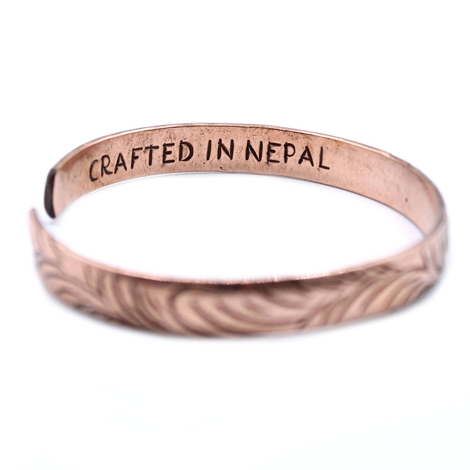 Alt Tag: Solid Copper Tibetan Bracelet – Slim Tribal Swirls, slim copper cuff bracelet with tribal swirl engraving and “CRAFTED IN NEPAL” stamp