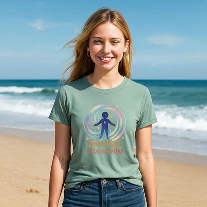 Mujer en la playa usando Somos Hijos las Estrellas Organica 100% Organic Cotton T-Shirt verde con diseño circular y texto "Somos hijos de las estrellas"