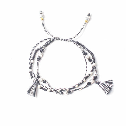 String & Beads Temple Bracelet – Balance of Nature, black and white string bracelet with metal beads and tassel ends on white background