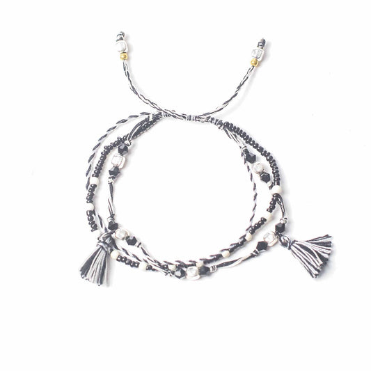 String & Beads Temple Bracelet – Balance of Nature, black and white string bracelet with metal beads and tassel ends on white background