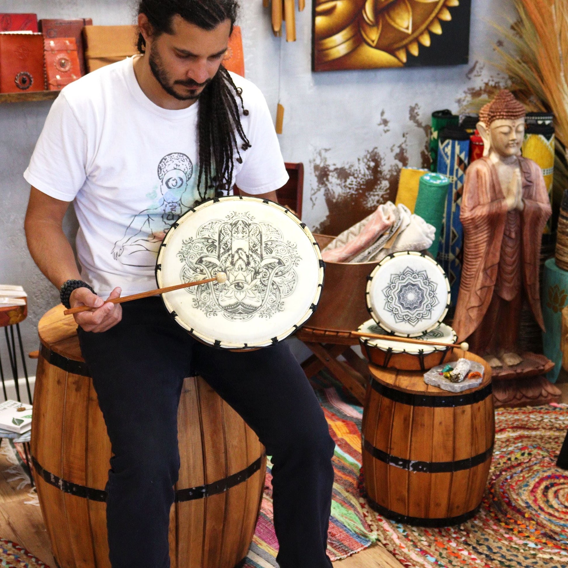 Suar Wood Hamsa Shamanic Drum – 30 CM played with mallet by seated musician, Hamsa symbol design on drum head