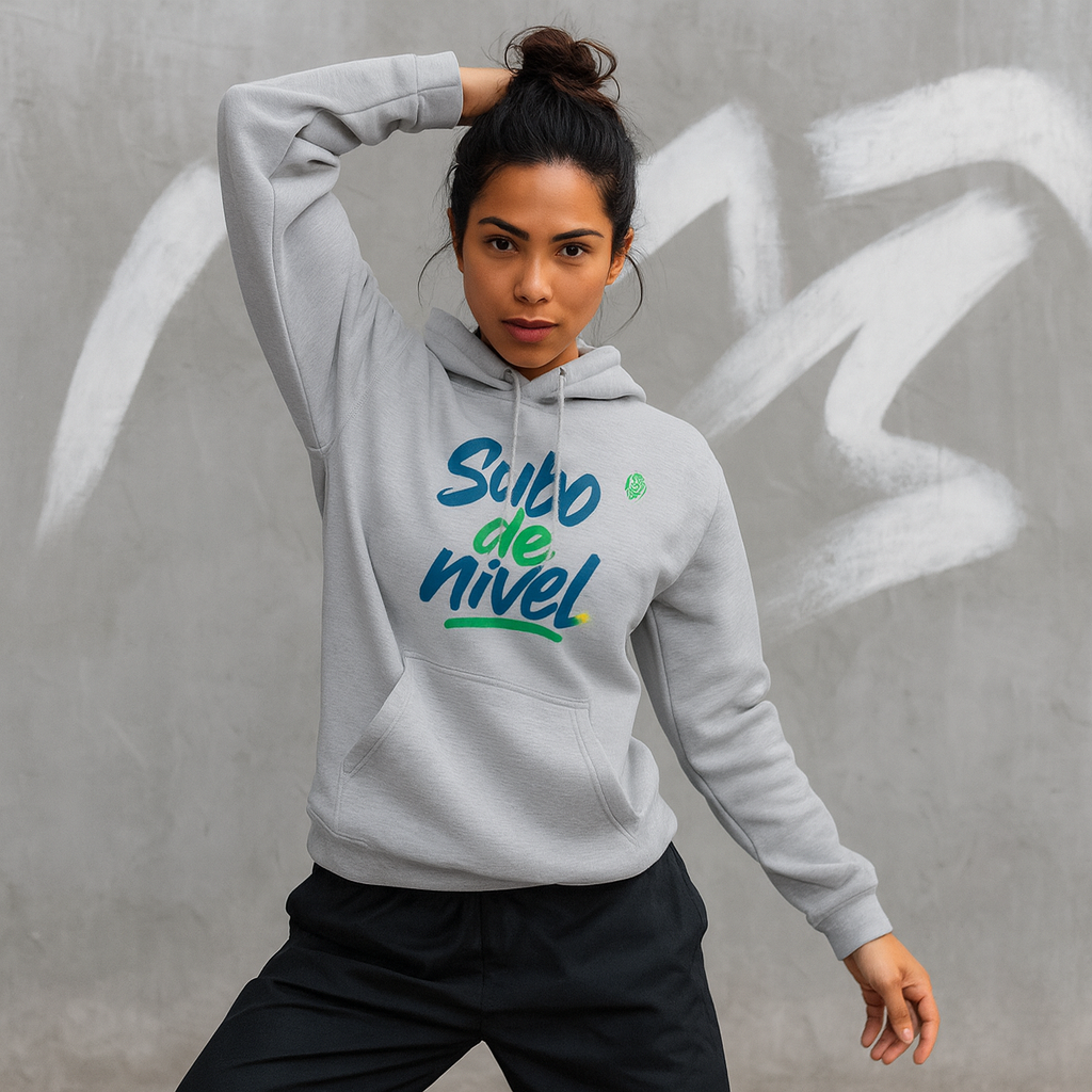 Alt Tag: Subo Nivel Drix Premium Unisex Hoodie gris con estampado “Subo de nivel”, modelo posando frente a pared con grafiti