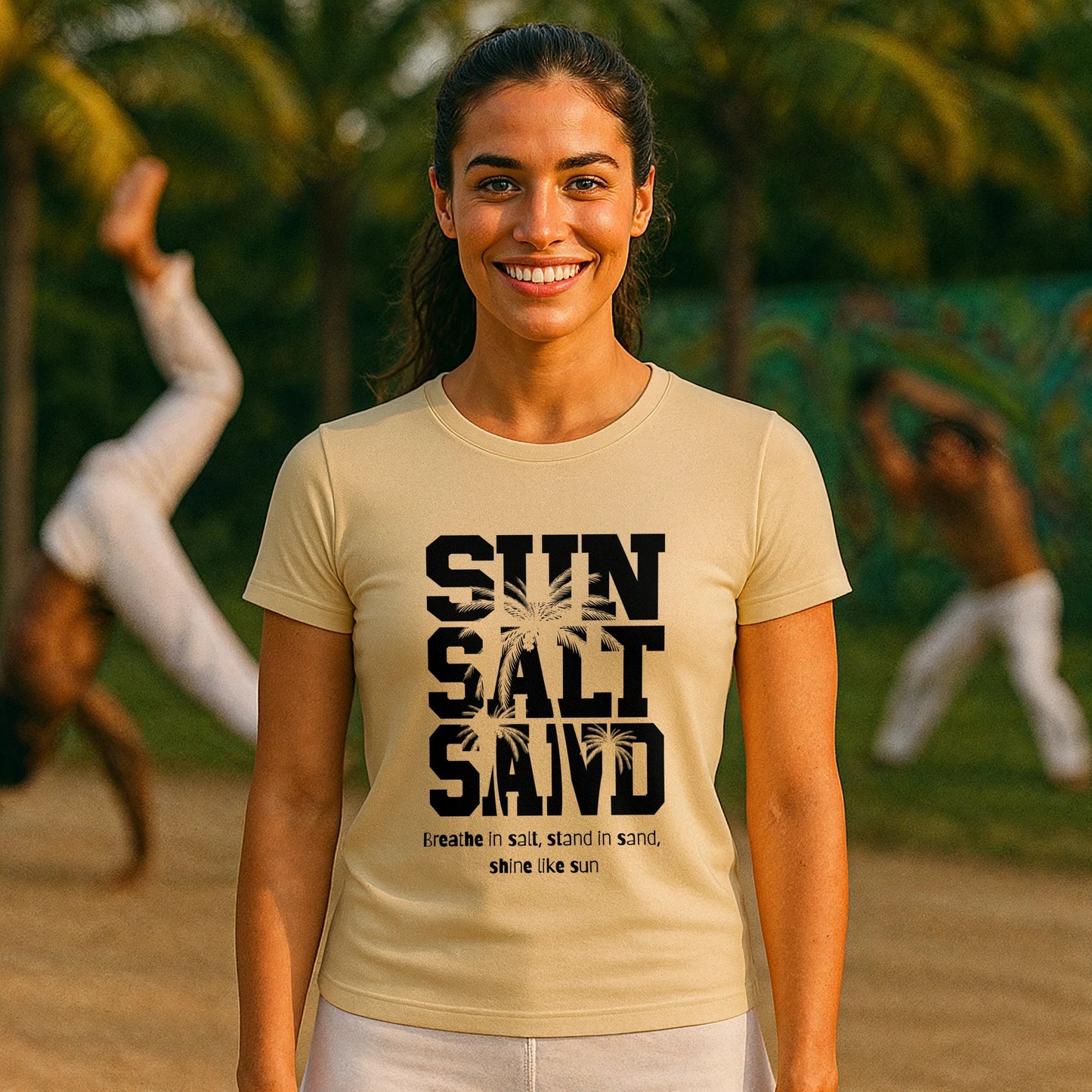Alt Tag: Sun Salt Sand 100% Organic Cotton T-Shirt worn by woman, beige graphic tee with “SUN SALT SAND” print, outdoor setting