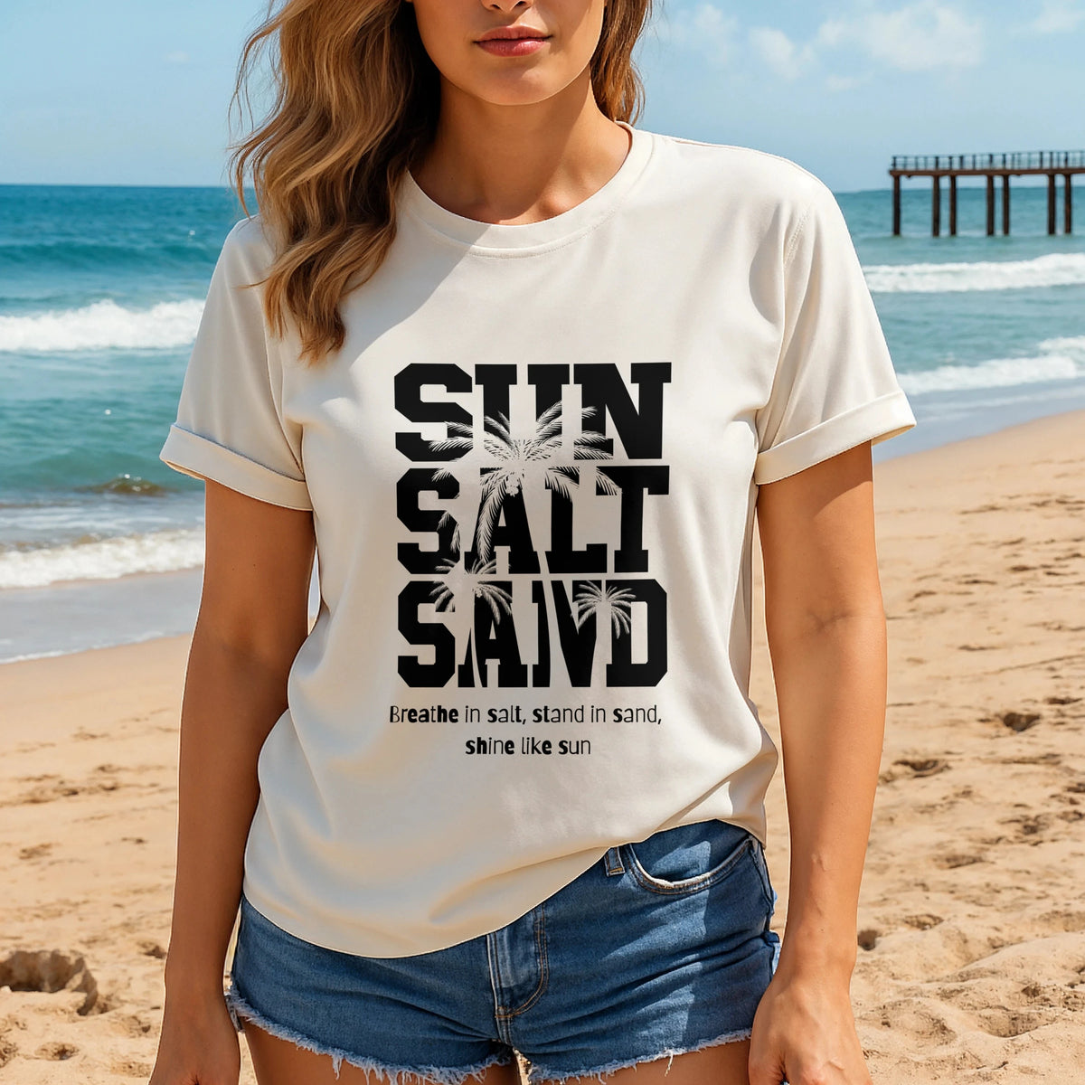Sun Salt Sand 100% Organic Cotton T-Shirt worn by woman on beach, white tee with bold graphic text