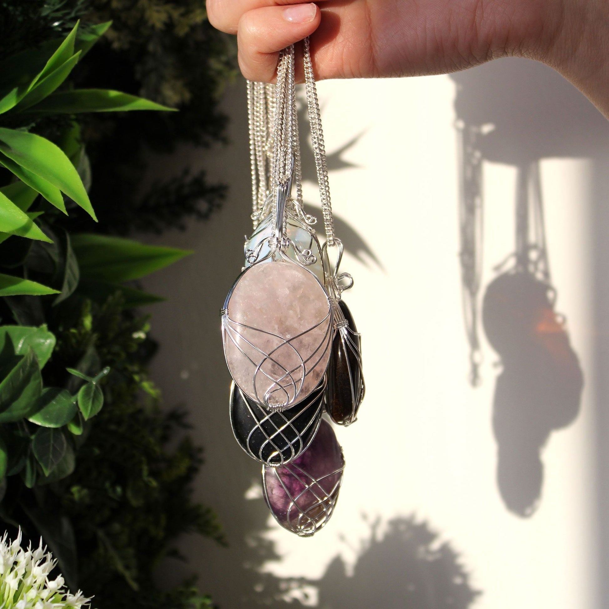 Swirl Wrapped Gemstone Necklace – Rose Quartz pendant with wire-wrapped pink gemstone on silver chain, held in hand outdoors