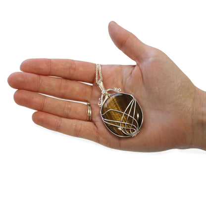 Swirl Wrapped Gemstone Necklace – Tiger Eye pendant with golden-brown tiger eye stone and silver swirl wire wrap on chain, held in hand