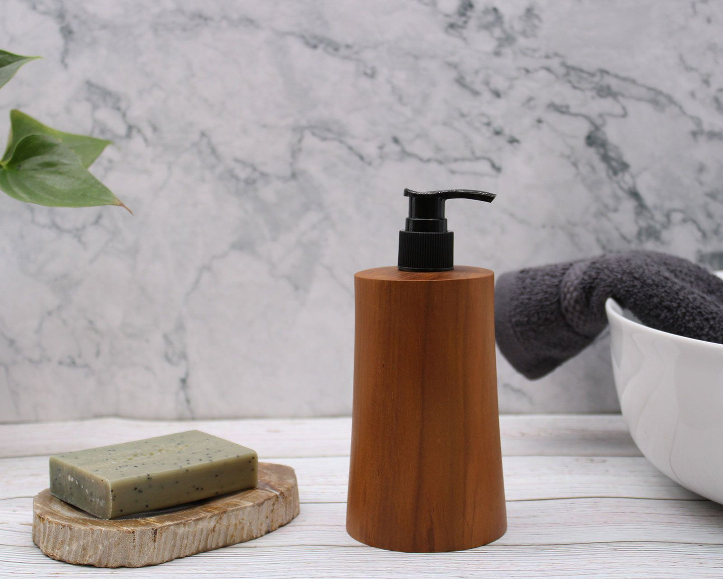 Teakwood Soap Dispenser – Taper Design on bathroom countertop with black pump, soap bar, towel and marble wall background
