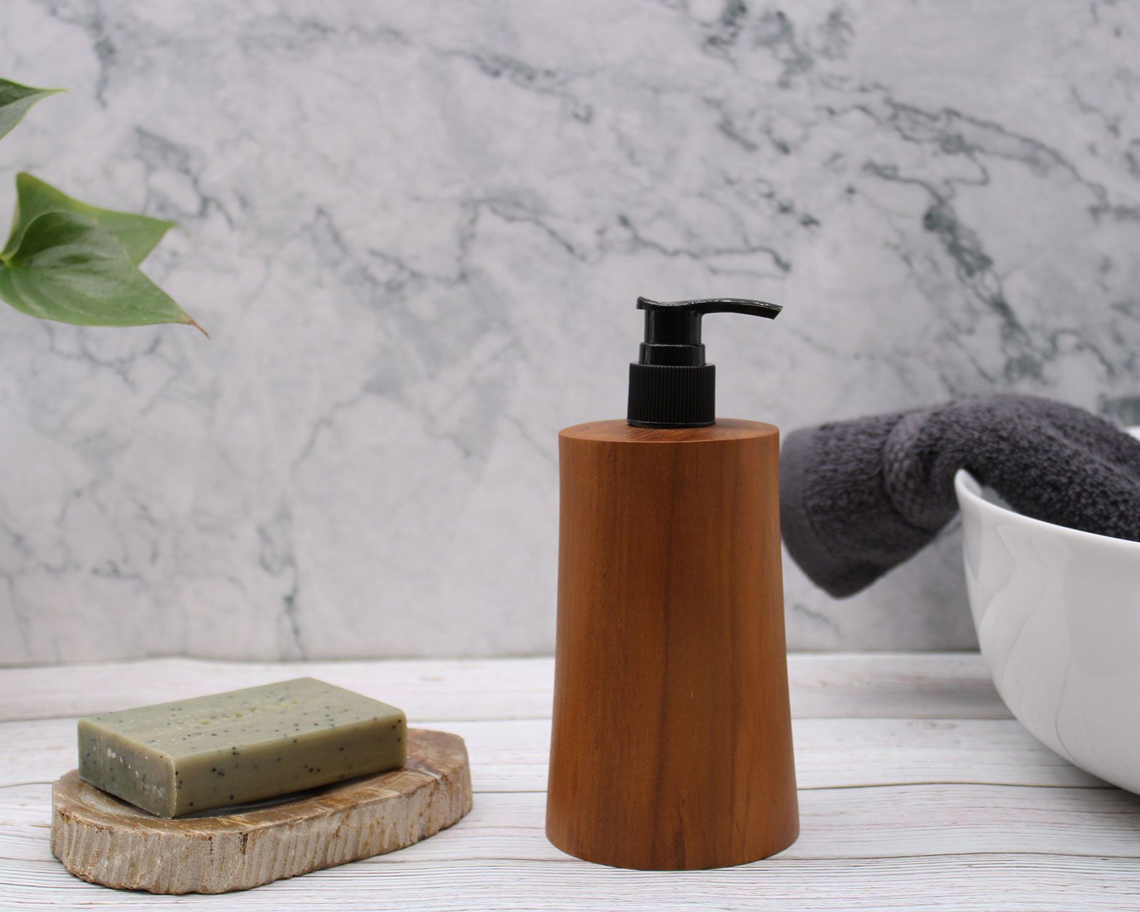 Teakwood Soap Dispenser – Taper Design on bathroom countertop with black pump, soap bar, towel and marble wall background