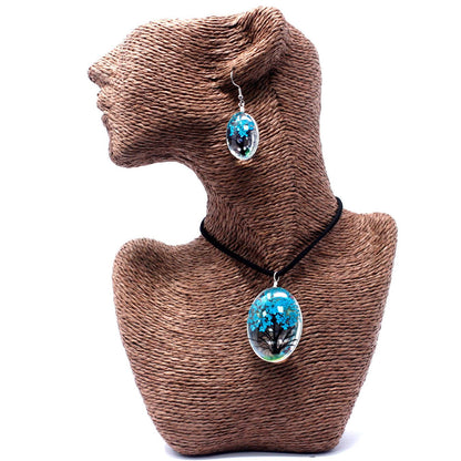 Teal Tree of Life Necklace – Glass & Flowers, oval glass pendant with teal tree motif on black cord, shown on mannequin bust