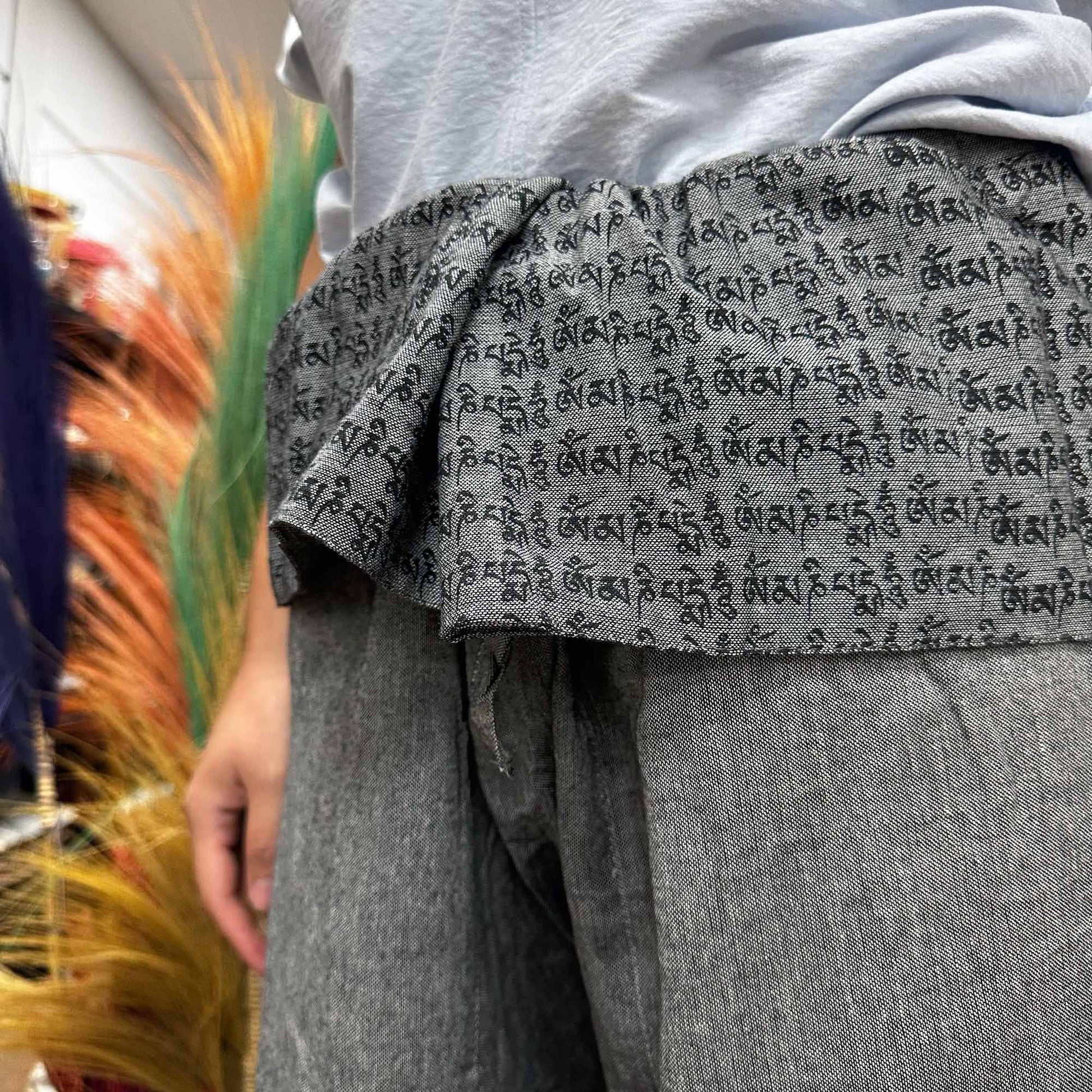 Alt Tag: Yoga- och festivalbyxor – Thai Fisherman Mandala Mantra i grått, närbild på grå yoga-wrapbyxor med omlottmidja och sanskritmantra-tryck