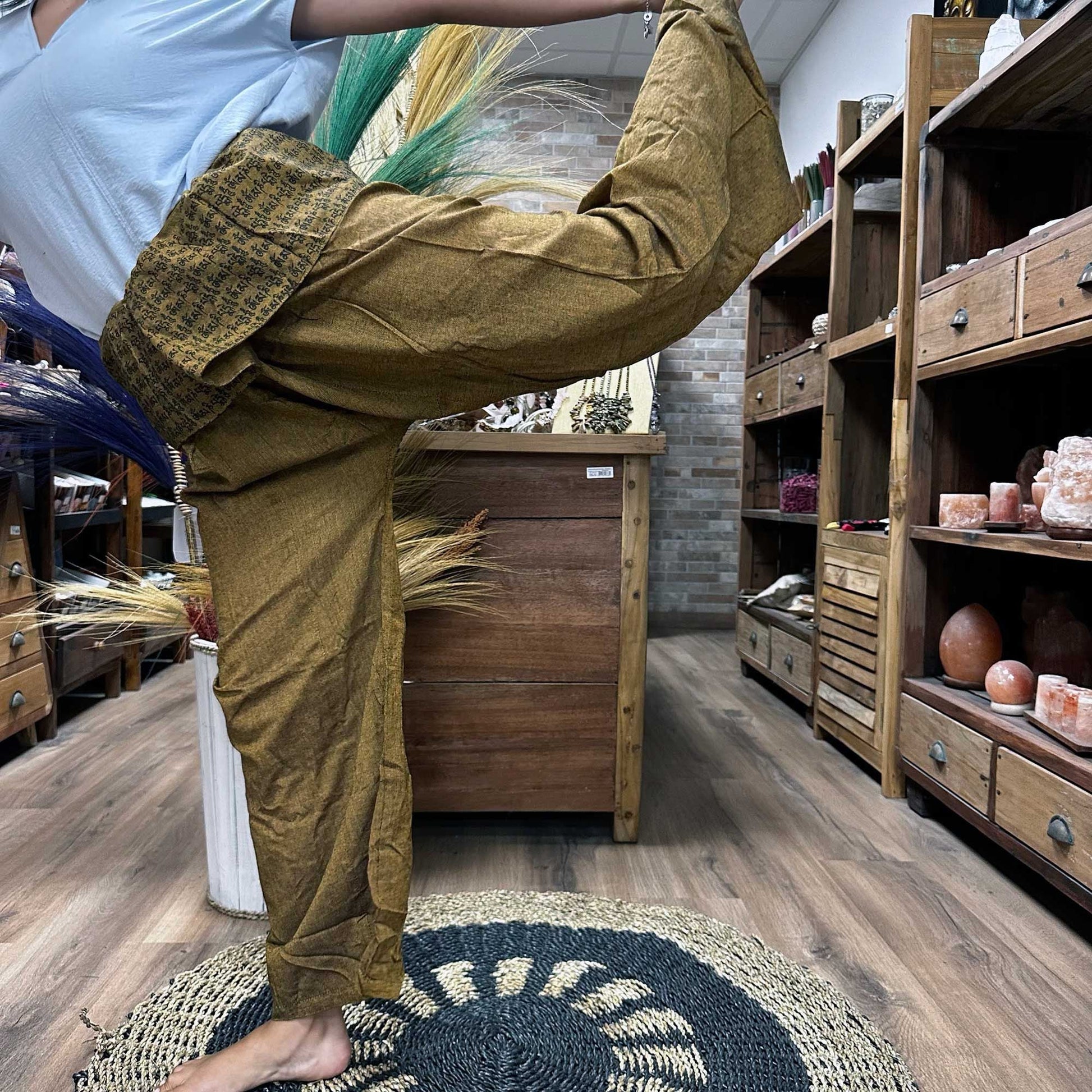 Yoga- och festivalbyxor – Thai Fisherman Mandala Mantra på Orange, burna i yogaposition, omlottbyxor i thailändsk fisherman-stil med mandala mantra-tryck