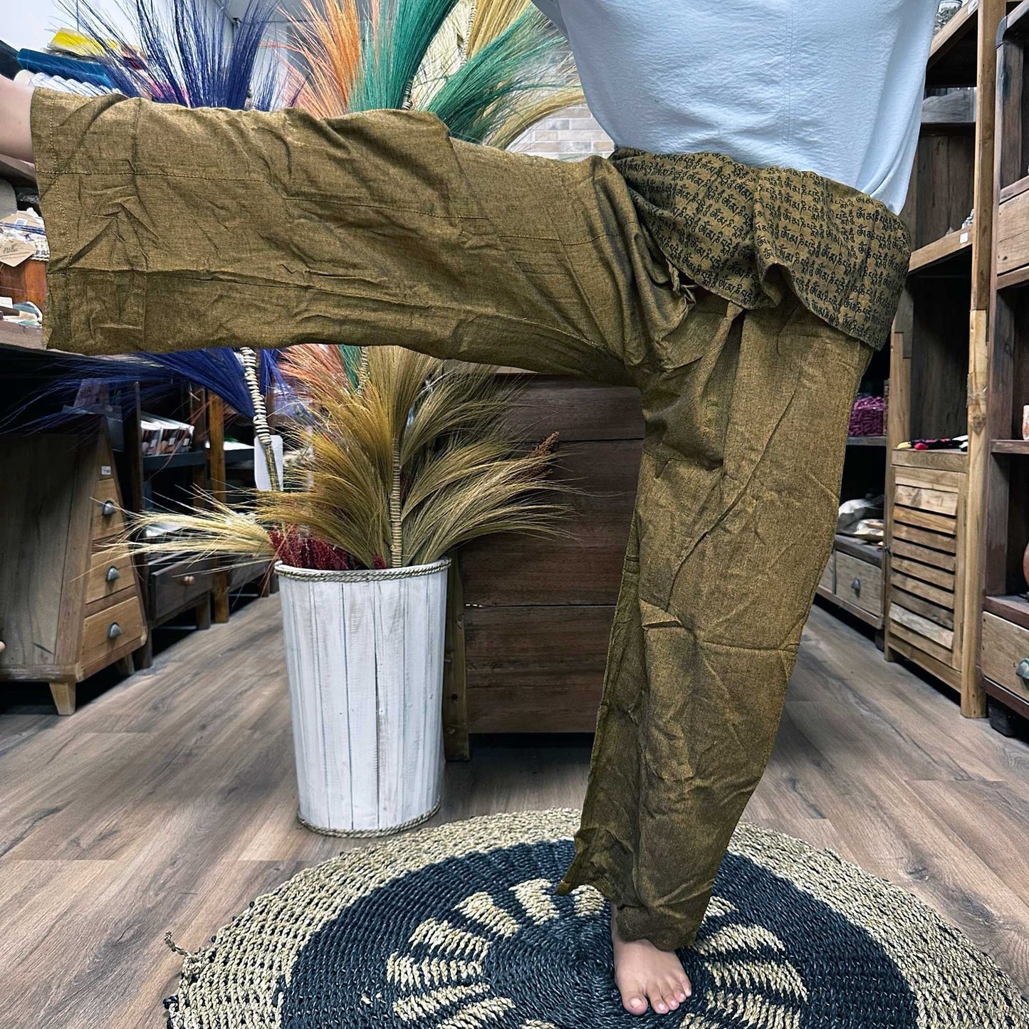 Yoga- och festivalbyxor – Thai Fisherman Mandala Mantra on Orange burna i yogaposition, thailändska fisherman-wrapbyxor med mandala-mantra-tryck