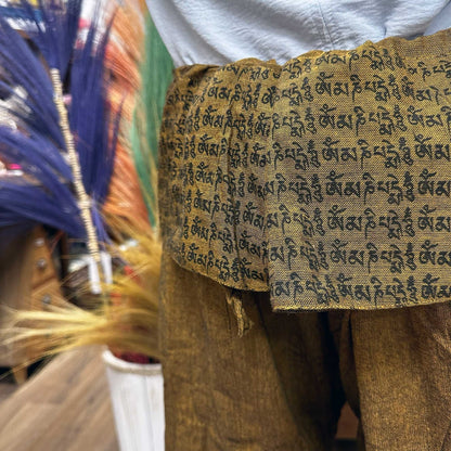 Yoga- och festivalbyxor – Thai Fisherman Mandala Mantra på orange, närbild av midjeomslag med sanskritmantra-tryck på orange tyg
