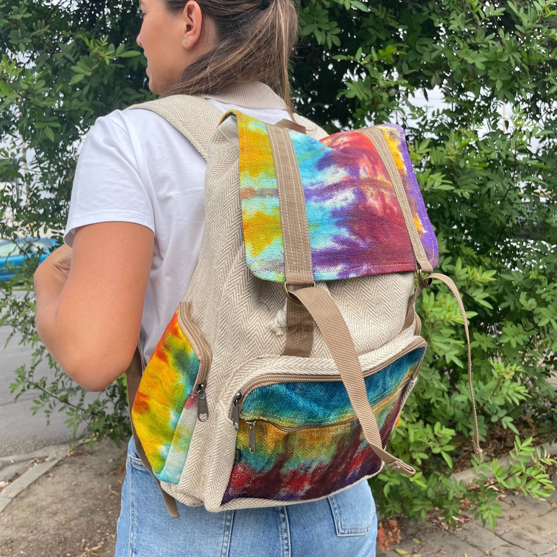 Alt Tag: Tiedye Hemp Large Square Backpack on model, square hemp-cotton backpack with colorful tie-dye flap and front pocket outdoors