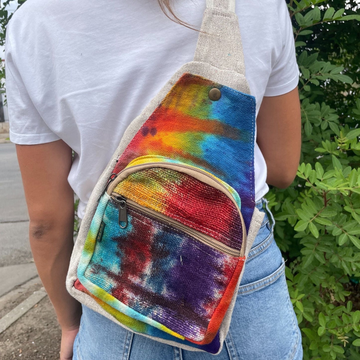 Alt Tag: Tiedye Hemp Sling Shoulder Bag All Natural From Kathmandu tie-dye hemp crossbody sling bag with front zipper pocket, worn outdoors