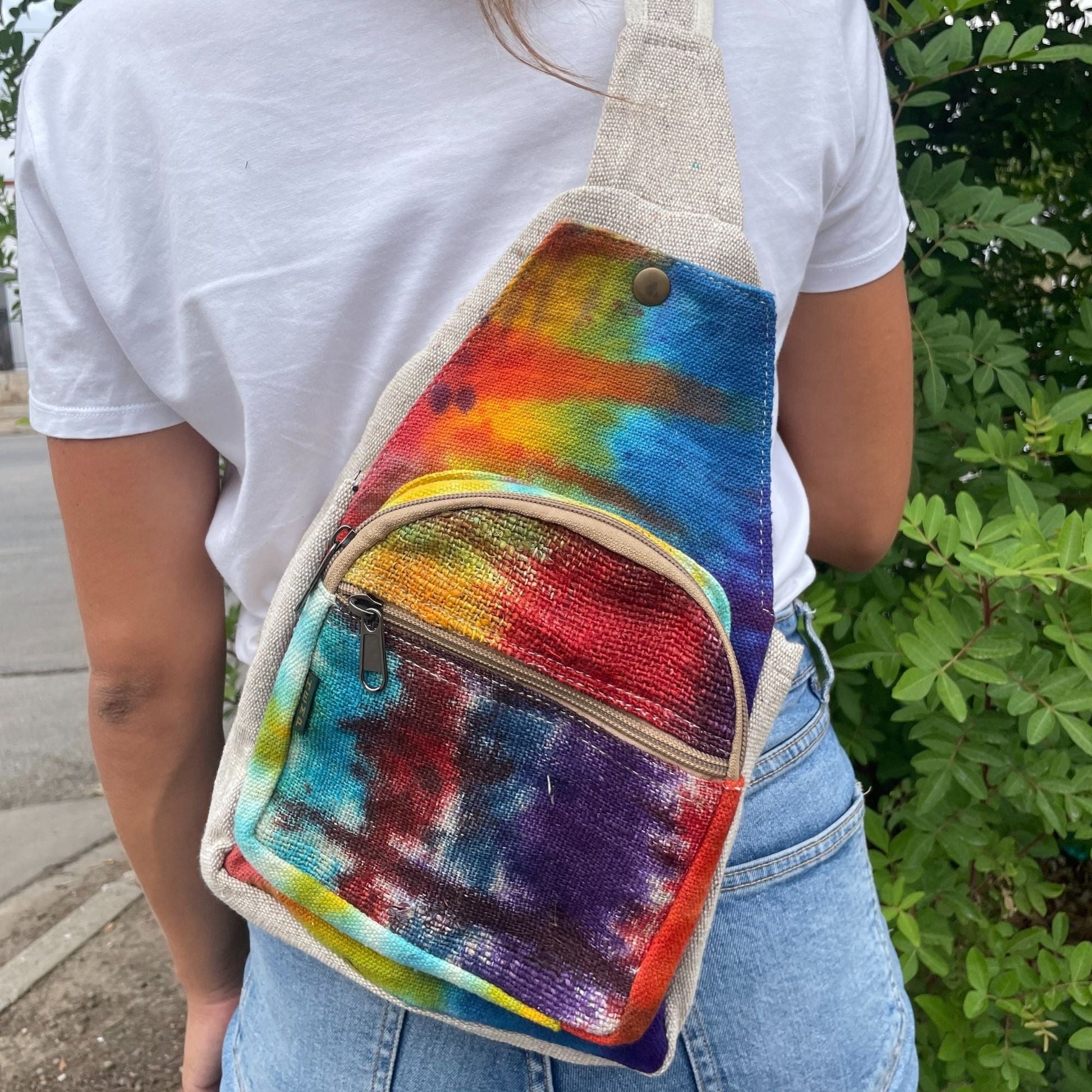 Alt Tag: Tiedye Hemp Sling Shoulder Bag All Natural From Kathmandu tie-dye hemp crossbody sling bag with front zipper pocket, worn outdoors