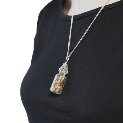 Alt Tag: Tiger Eye Bottled Gemstones Necklace – Natural Stone glass bottle pendant with tiger eye chips on silver chain, worn on black top