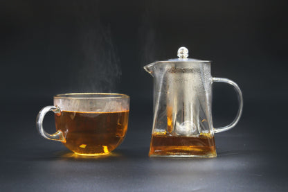 Tower Shape Glass Infuser Teapot – 750ML with stainless steel infuser, clear glass teapot and cup with brewed tea on dark background