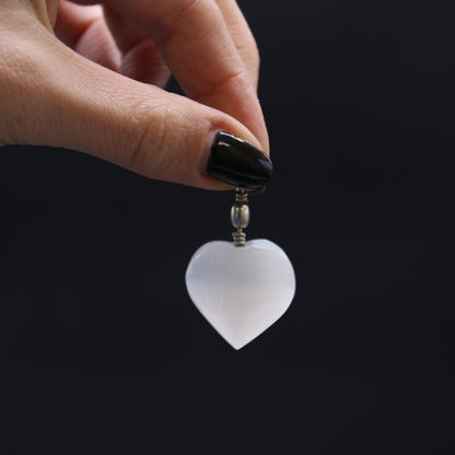 Alt Tag: Translucent Selenite Heart Pendant – 4x2.5 CM held by hand, nearly translucent heart-shaped selenite stone charm