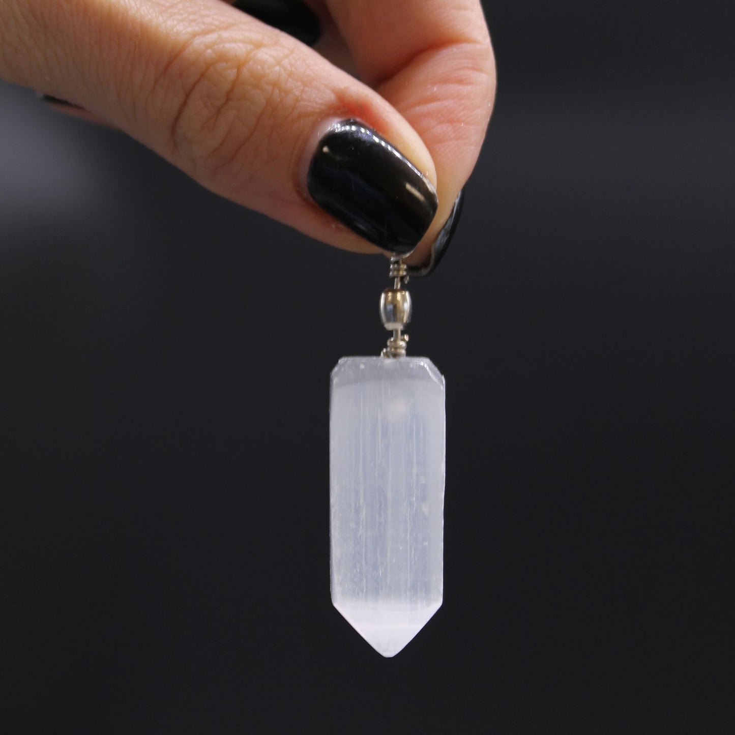 Alt Tag: Translucent Selenite Pendant – 5x1.5 CM held by hand, translucent selenite crystal point pendant with metal bail