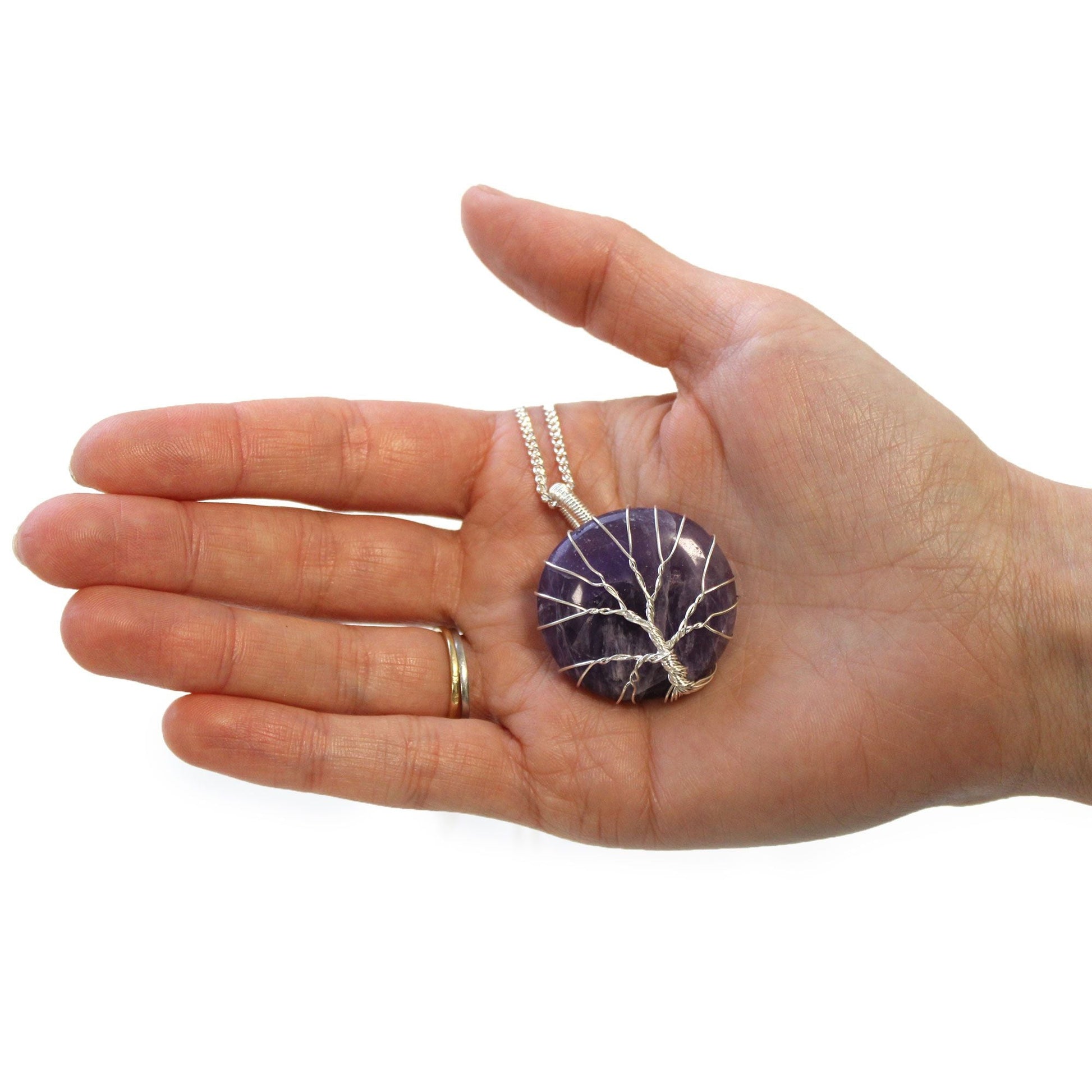 Alt Tag: Tree of Life ädelstenshalsband – ametisthänge i hand, rund lila ametiststen lindad med tree-of-life-tråd på kedja