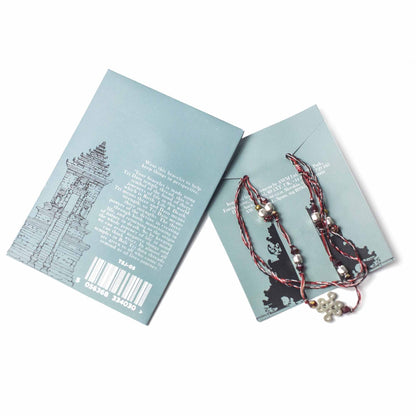 Tri Datu Temple String Bracelet – Journey of Life sobre Brochure, geflochtenes Fadenarmband in Rot Schwarz Weiß mit Metallperlen