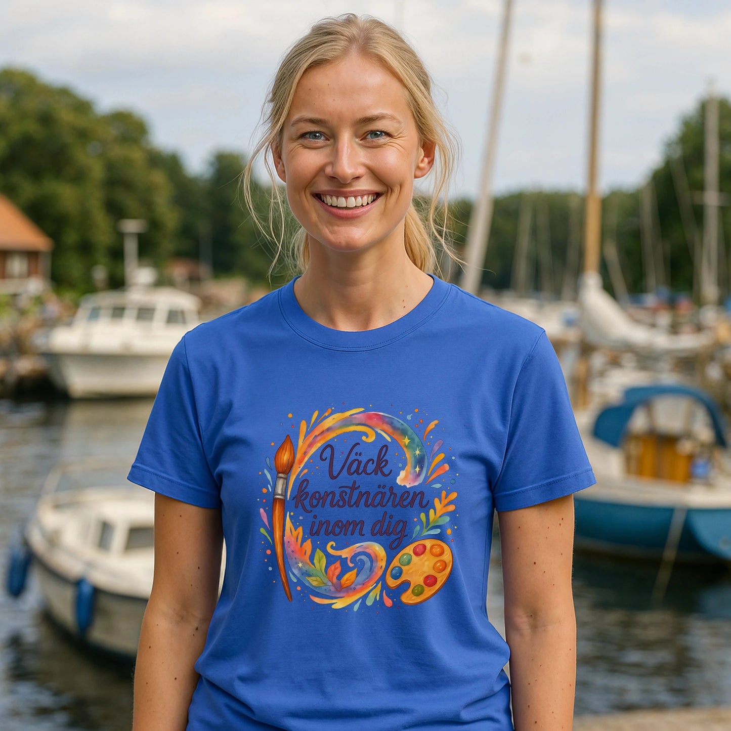 Väck Konstnären Inom Dig Waldorf Sustainable Unisex Tee blå t-shirt med konstmotiv, modell bär tröjan vid marina