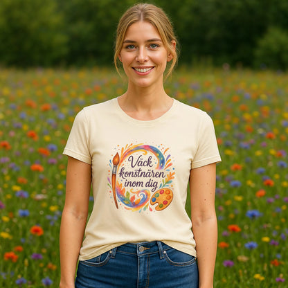 Väck Konstnären Inom Dig Waldorf Sustainable Unisex Tee på modell, beige t-shirt med färgglad konstnärsgrafik i blomsteräng