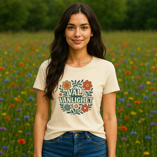 Välj Vänlighet Bomulls 100% Organic Cotton T-Shirt worn by woman, cream tee with floral “Välj Vänlighet” print in meadow