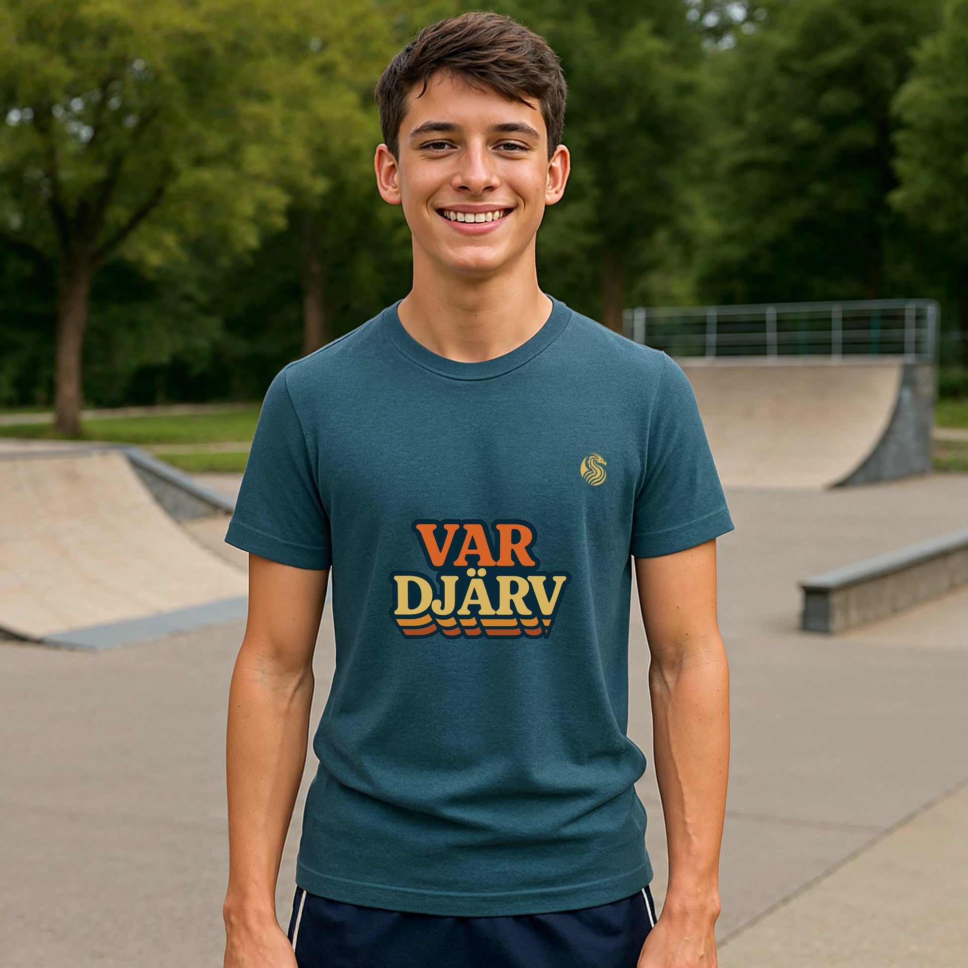 Alt Tag: Var Djärv Ungdom 100% Organic Cotton T-Shirt en modelo joven en skatepark, camiseta azul con logo VAR DJÄRV al frente