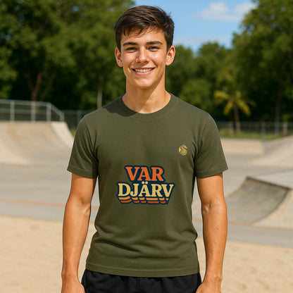 Var Djärv Ungdom 100% Organic Cotton T-Shirt en verde oliva, modelo sonriendo al aire libre en skatepark con logo VAR DJÄRV