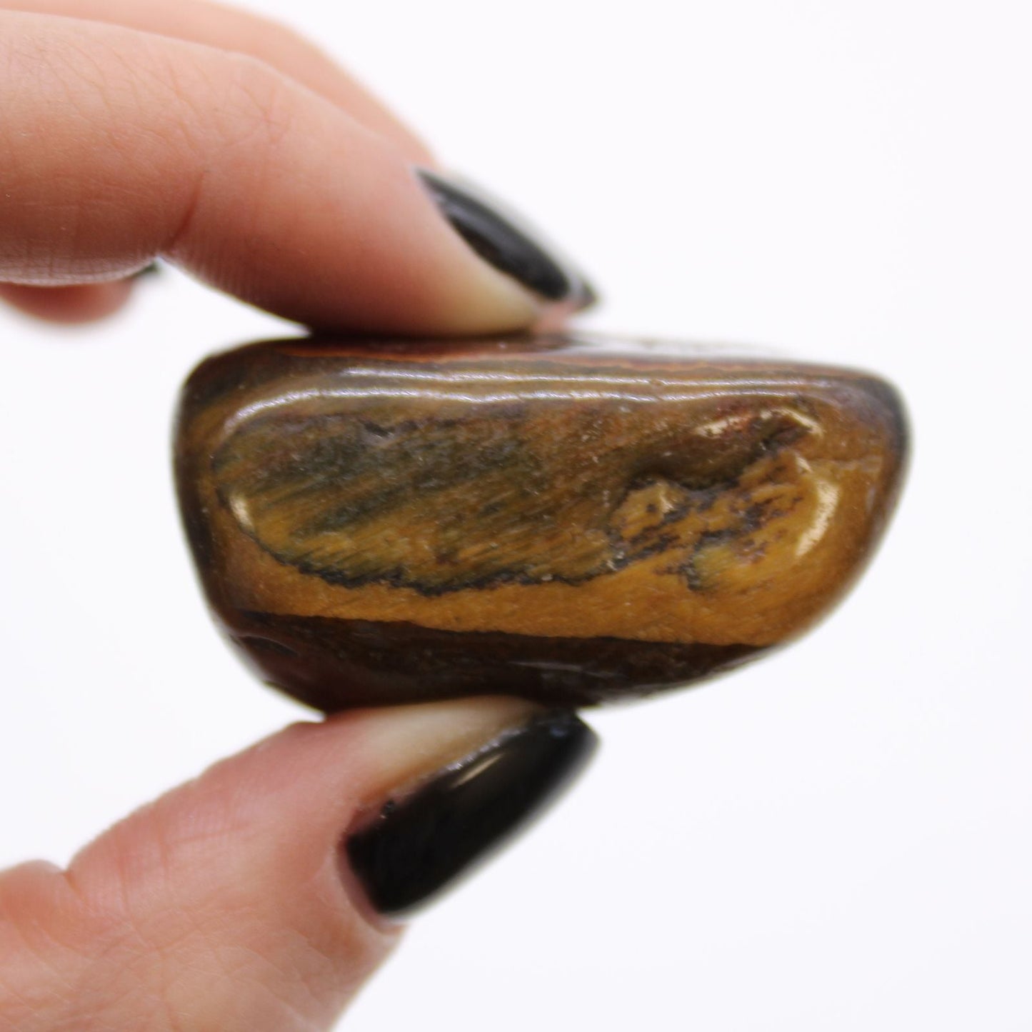 Alt Tag: Variegated Tiger’s Eye Tumble Stones – 6-Piece Set, close-up of polished variegated tiger’s eye stone held between fingers