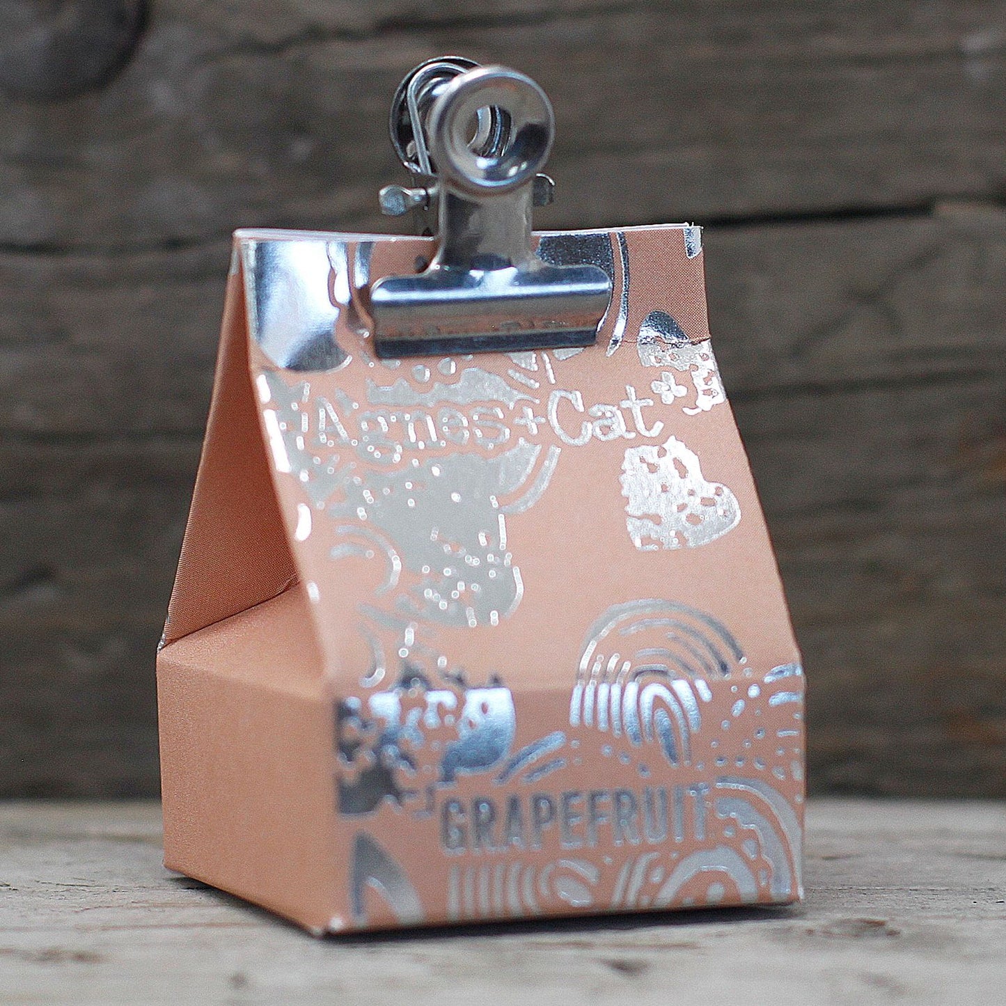Vegan Grapefruit Lip Balm – 12G packaging with grapefruit-themed design and metal clip, on rustic wooden background