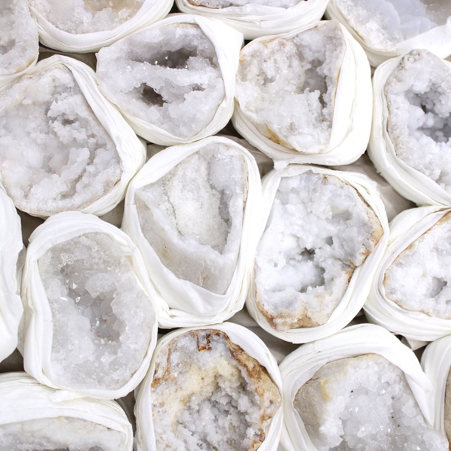 Alt Tag: Vibrant Calcite Mineral Specimens – Approx 32 Pieces, close-up of white calcite crystal geode halves wrapped in protective paper