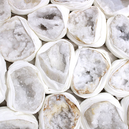 Alt Tag: Vibrant Calcite Mineral Specimens – Approx 32 Pieces, close-up of white calcite crystal geode halves wrapped in protective paper