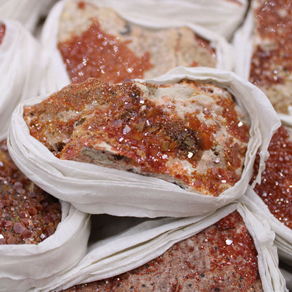 Alt Tag: Vibrant Vanadinite Mineral Specimens – Approx. 20 Pieces, crystal clusters on rock matrix wrapped in paper, close-up mineral lot