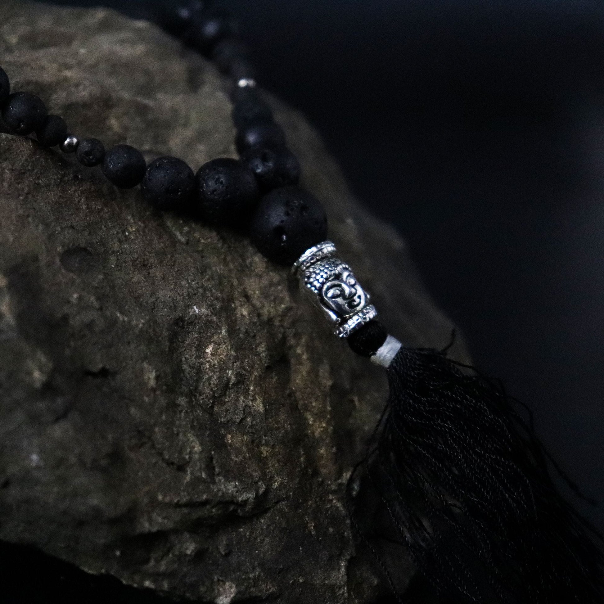 Alt Tag: Volcanic Bead Necklace – Grounding Energy con cuentas negras de piedra volcánica, detalle plateado tipo Buda y borla negra