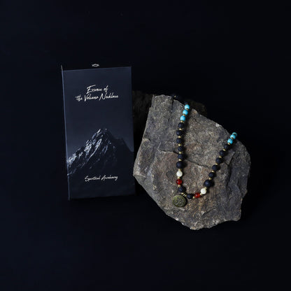 Volcanic Bead Om Necklace – 42 CM on rock display with gemstone beads and Om pendant, photographed beside product booklet
