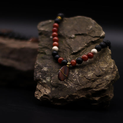 Volcanic Beads Necklace – 42 CM with lava stone and red gemstone beads, handcrafted in Indonesia, displayed on natural rock