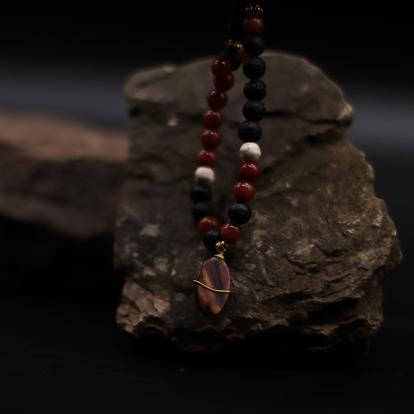 Volcanic Beads Necklace – 42 CM with lava stone and red gemstone beads, handmade in Indonesia, displayed on dark rock