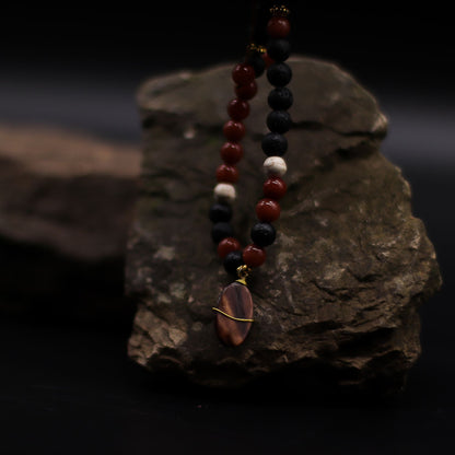 Volcanic Beads Necklace – 42 CM with lava stone and red gemstone beads, handmade in Indonesia, displayed on dark rock