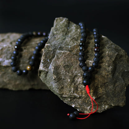 Alt Tag: Volcanic Lava & Tiger's Eye Necklace – 42CM with black volcanic stone beads and tiger’s eye accents on rock backdrop