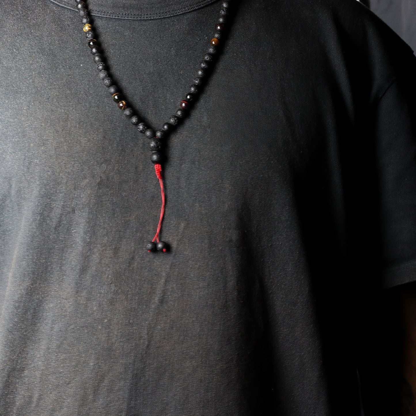 Volcanic Lava & Tiger's Eye Necklace – 42CM black beaded necklace with red tassel on model wearing black shirt