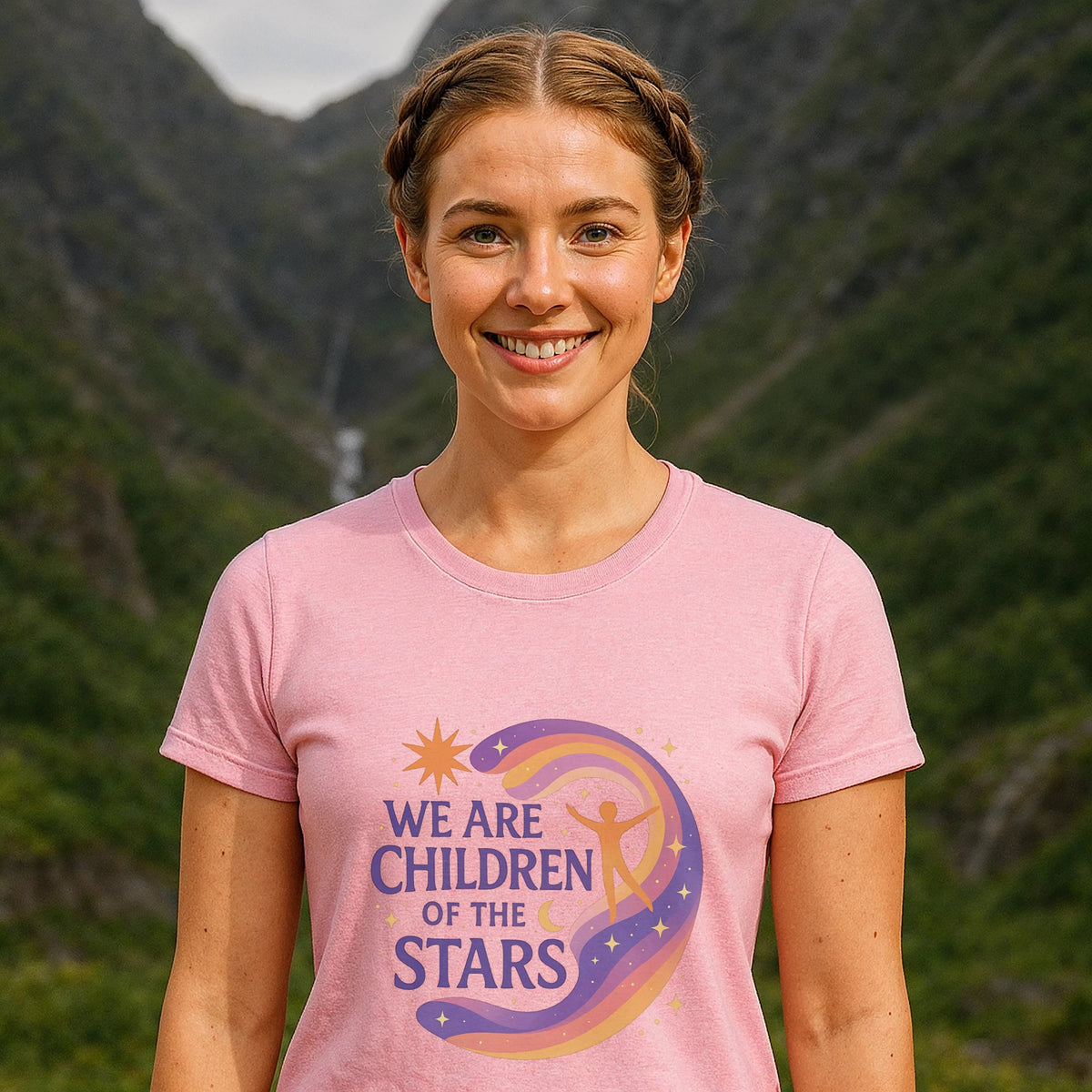 We Are Children Of The Stars 100% Organic Cotton T-Shirt on woman wearing pink graphic tee outdoors with mountains
