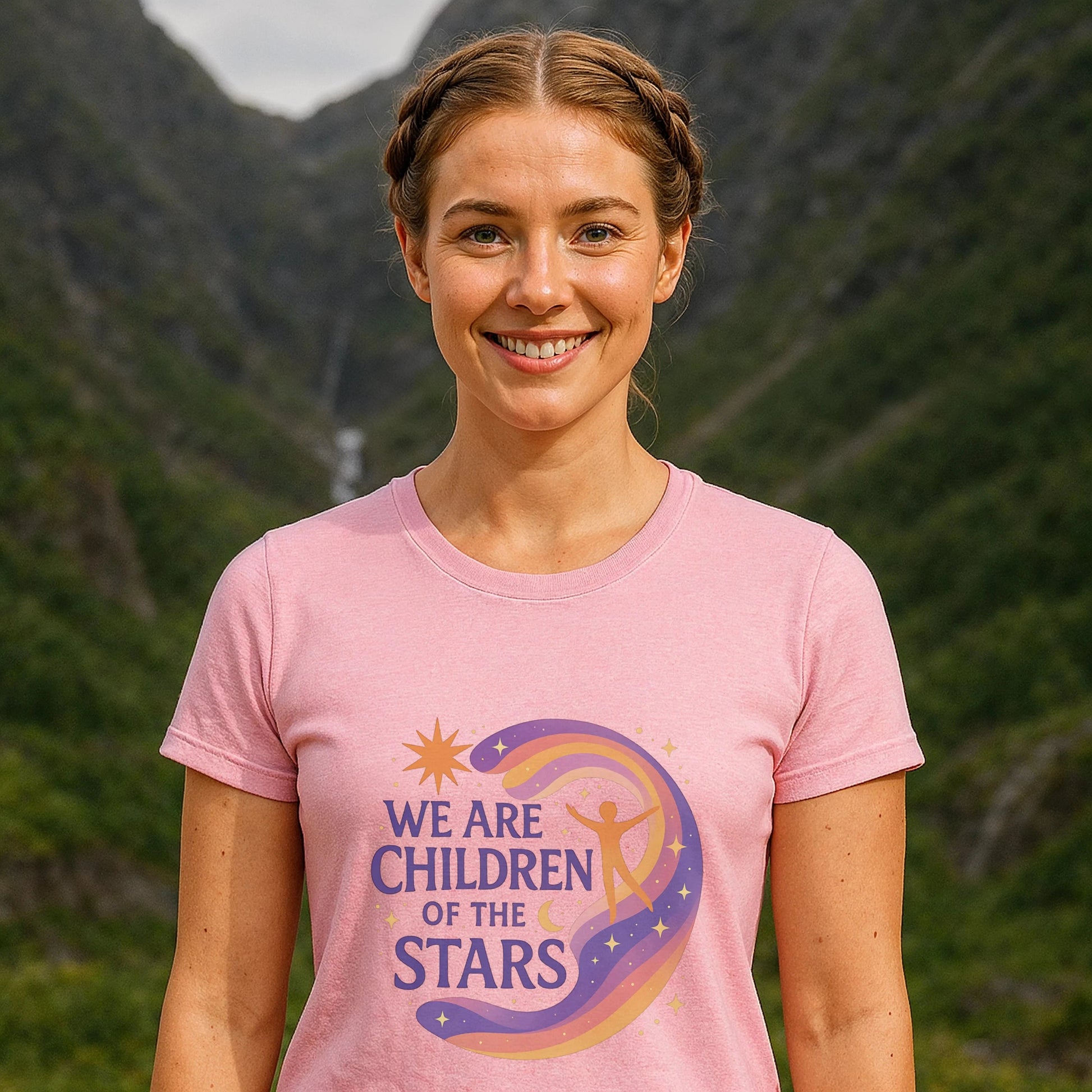 We Are Children Of The Stars 100% Organic Cotton T-Shirt on woman wearing pink graphic tee outdoors with mountains