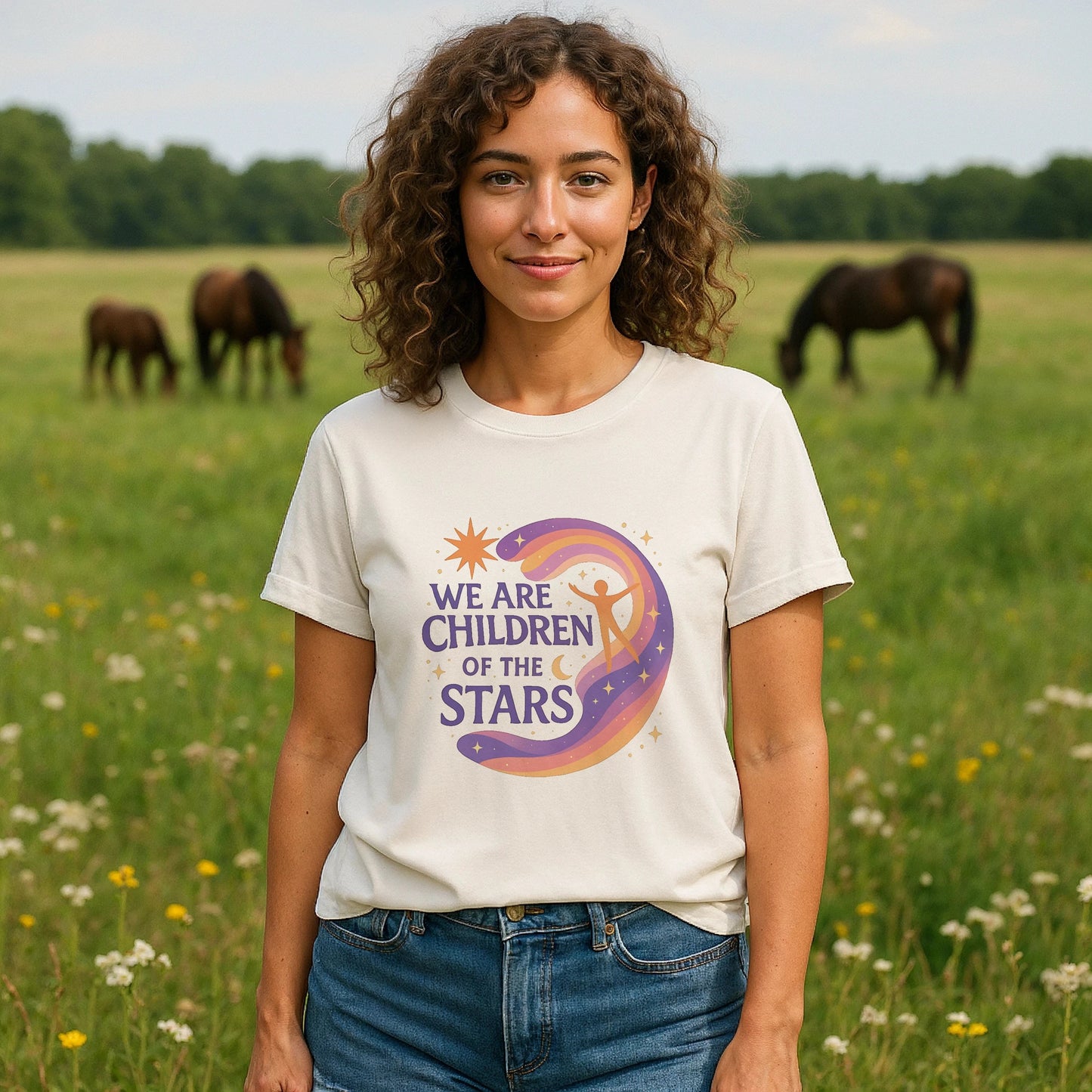 We Are Children Of The Stars 100% Organic Cotton T-Shirt worn by woman, cream tee with colorful moon and star graphic, outdoors