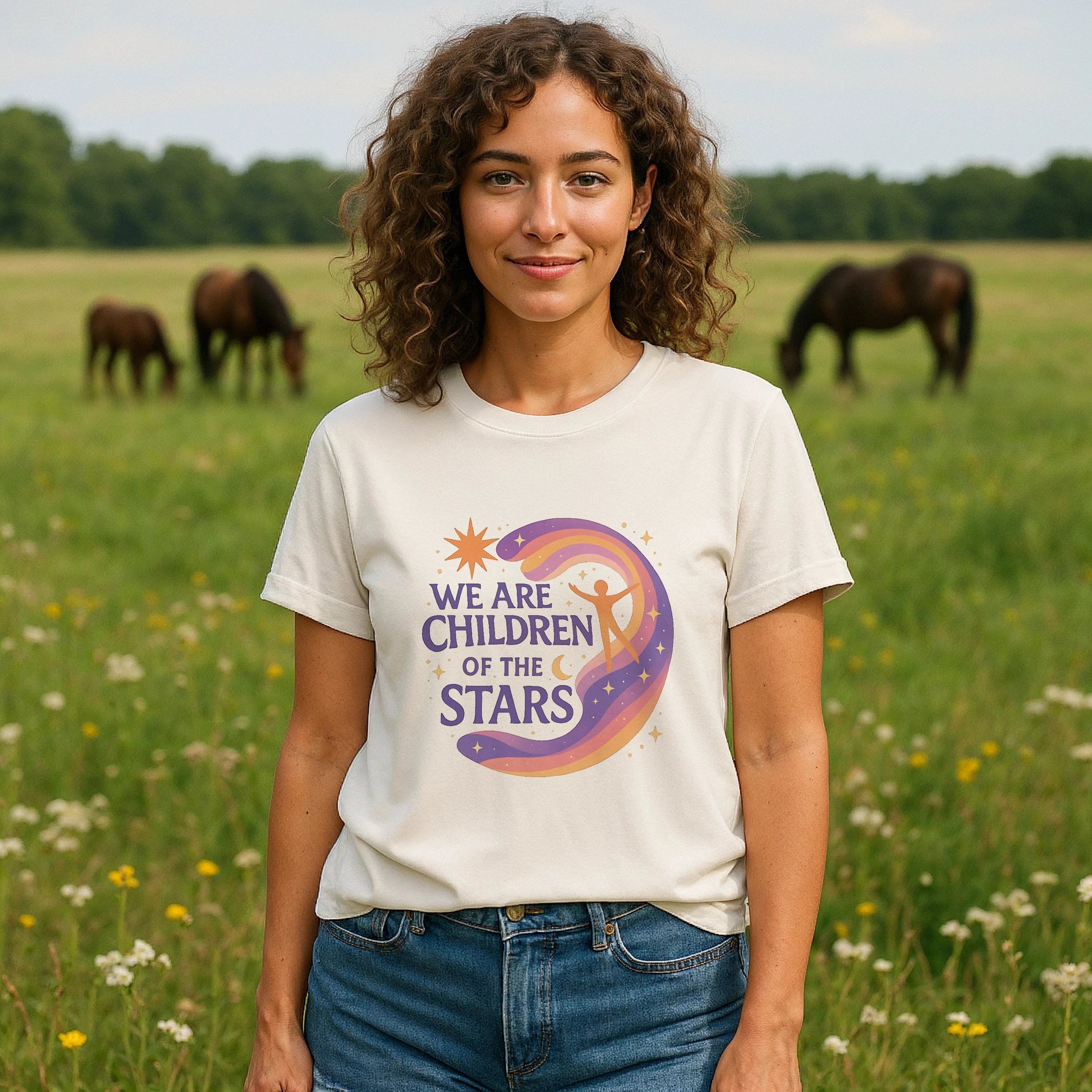 We Are Children Of The Stars 100% Organic Cotton T-Shirt worn by woman, cream tee with colorful moon and star graphic, outdoors