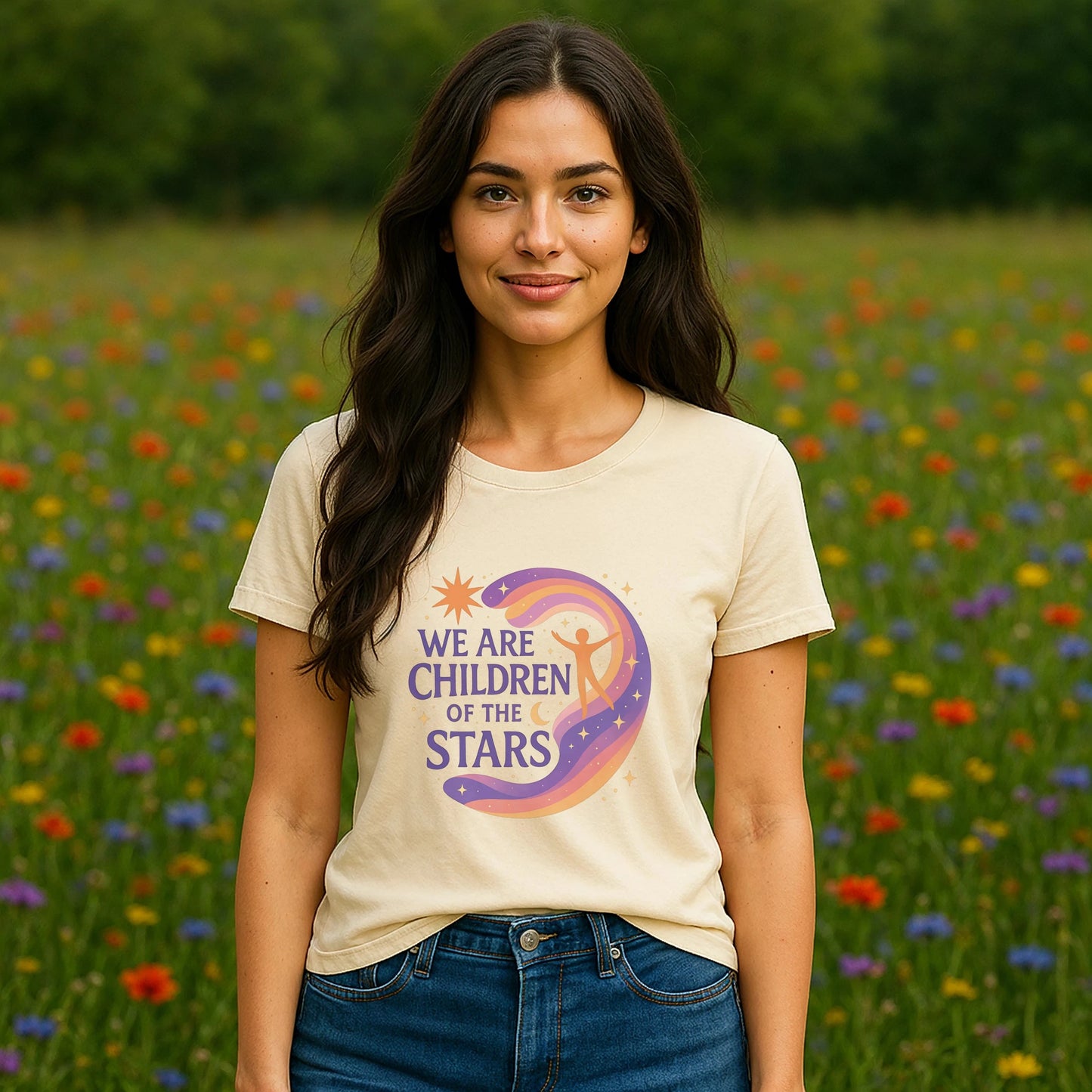 Alt Tag: Model wearing We Are Children Of The Stars 100% Organic Cotton T-Shirt with celestial graphic, outdoors in a wildflower field