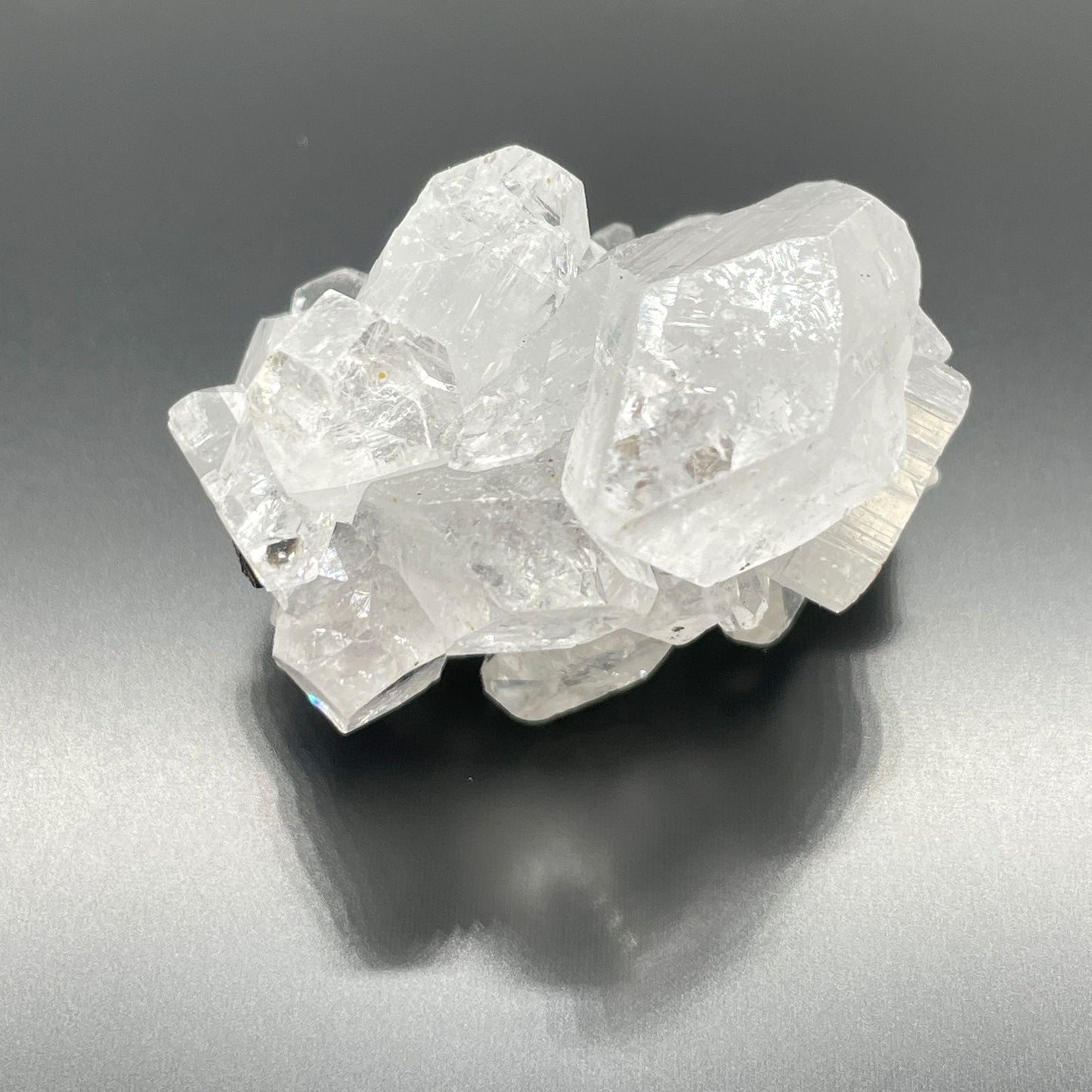 White Apophyllite Clusters – 20–30 MM natural white crystal cluster specimen with clear, reflective points on dark background